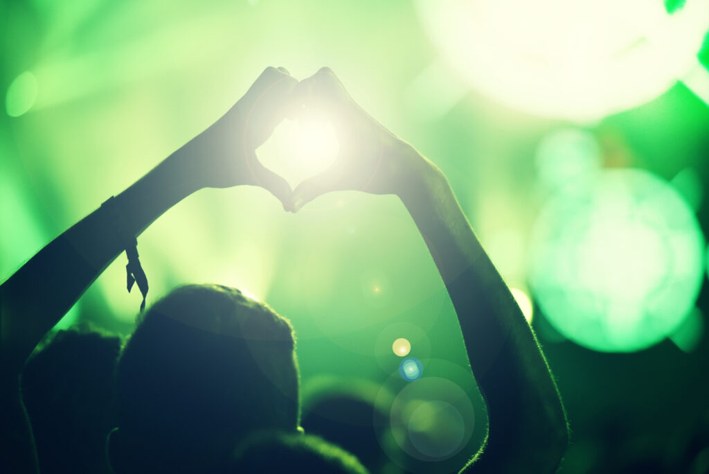 Crowd at a music concert, audience raising hands up, Silhouette of hands on a concert in front of bright stage lights
