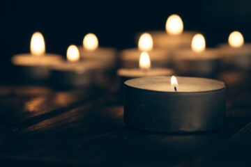 candles burning in darkness over black background. commemoration concept.